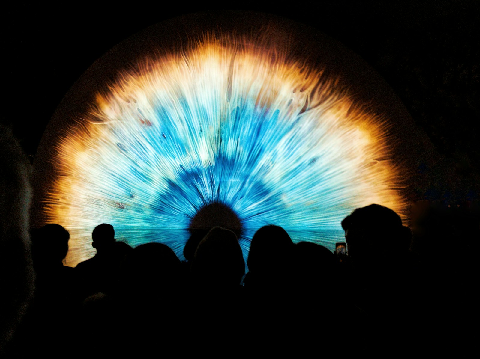 a group of people standing in front of a projection of an eye
